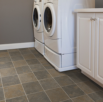 Laundry room with front-load washing machines and dark stone-look tile flooring.