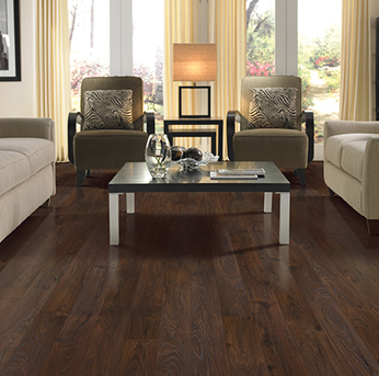 A cozy, well-lit living room featuring dark-stained hardwood flooring, neutral sofas and armchairs, and a low-profile coffee table