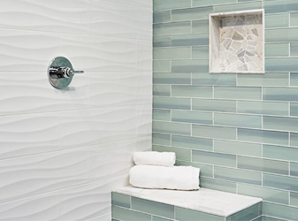 Seafoam green glass subway tile and textured white wall tile in a shower.