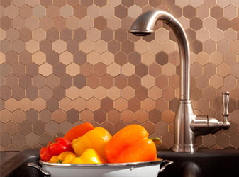 Copper hexagon mosaic tile backsplash behind a kitchen faucet.