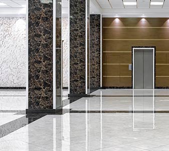 Commercial lobby with polished white tile floors and marble pillars.